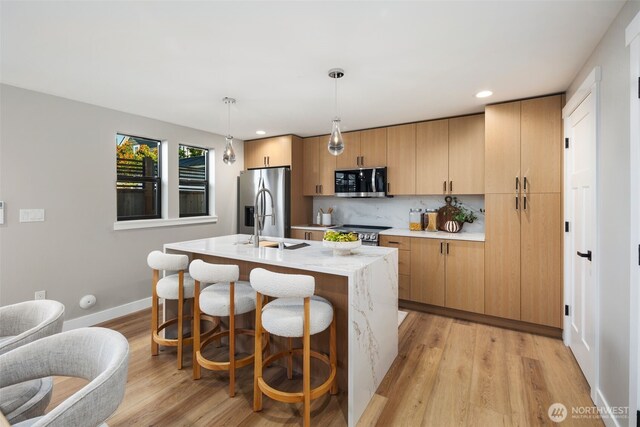 3720 36th Ave SW Unit B, Seattle, WA 98126 - kitchen with appliances with stainless steel finishes, an island with sink, light wood-style floors, decorative backsplash, and recessed lighting