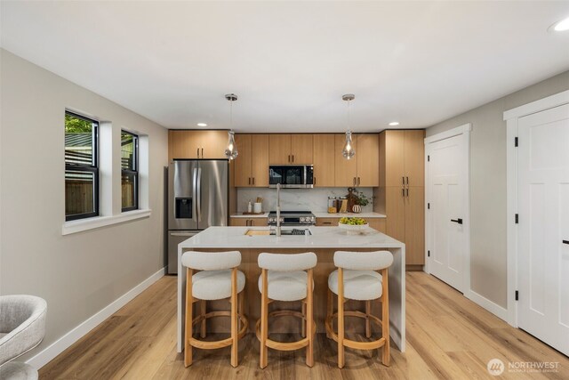 3720 36th Ave SW Unit B, Seattle, WA 98126 - kitchen featuring stainless steel appliances, light countertops, light wood-style flooring, recessed lighting, and a kitchen island with sink