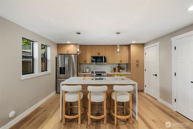 3720 36th Ave SW Unit B, Seattle, WA 98126 - kitchen featuring stainless steel appliances, light countertops, light wood-style floors, tasteful backsplash, and baseboards