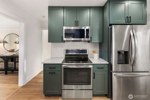 3722 36th Ave SW, Seattle, WA 98126 - kitchen featuring appliances with stainless steel finishes, green cabinetry, backsplash, light wood-style flooring, and light stone countertops