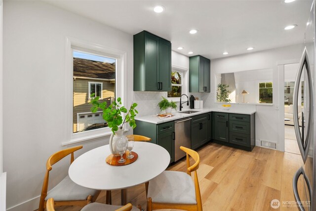 3722 36th Ave SW, Seattle, WA 98126 - kitchen featuring green cabinetry, a sink, stainless steel appliances, light countertops, and light wood-style floors