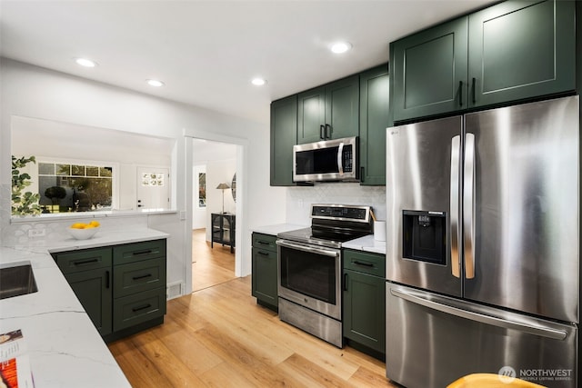 3722 36th Ave SW, Seattle, WA 98126 - kitchen with stainless steel appliances, green cabinets, light stone counters, backsplash, and light wood-type flooring