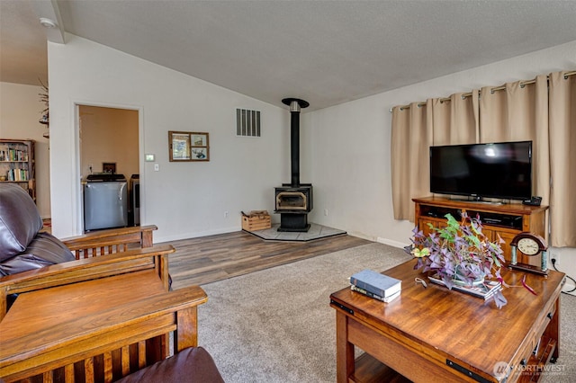 424 Maranatha, Kelso, WA 98626 - living area featuring lofted ceiling, carpet flooring, a wood stove, wood finished floors, and baseboards