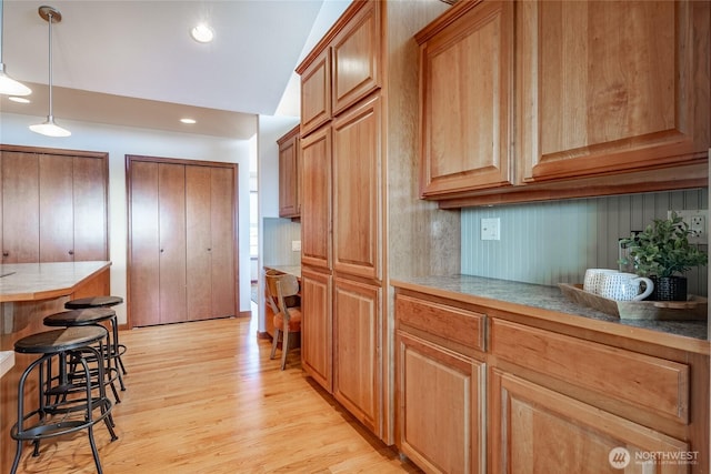 8022 Makah Rd, Blaine, WA 98230 - kitchen with light wood-type flooring, a kitchen breakfast bar, pendant lighting, brown cabinetry, and recessed lighting