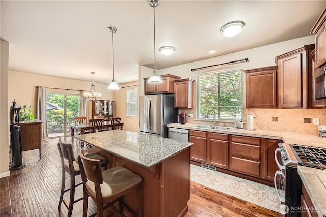 4306 Maple St SE, Olympia, WA 98501 - kitchen featuring appliances with stainless steel finishes, light wood-type flooring, a kitchen bar, decorative backsplash, and a kitchen island