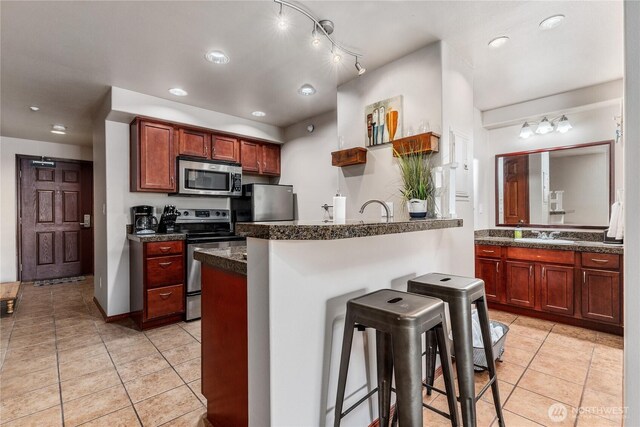 322 W Woodin Ave Unit 620, Chelan, WA 98816 - kitchen with stainless steel appliances, a breakfast bar area, light tile patterned floors, a peninsula, and recessed lighting
