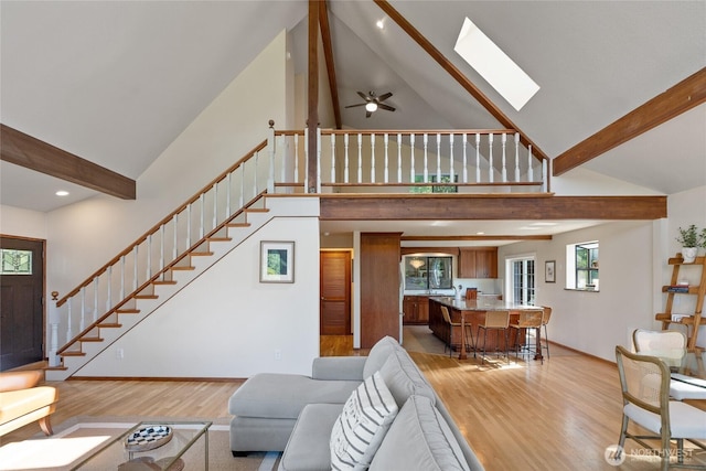 19709 Whiteman Cove Rd SW, Longbranch, WA 98351 - living room with high vaulted ceiling, light wood-type flooring, stairway, a skylight, and beam ceiling
