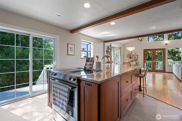 19709 Whiteman Cove Rd SW, Longbranch, WA 98351 - kitchen featuring stainless steel electric stove, french doors, dark stone counters, a center island, and light tile patterned flooring
