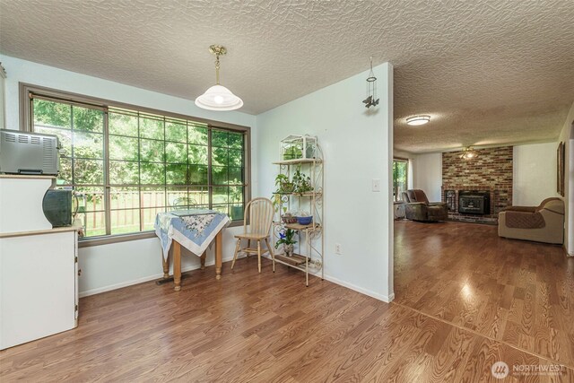 29139 NE Hammond Ct, Battle Ground, WA 98604 - dining room featuring wood finished floors, a textured ceiling, a fireplace, and baseboards