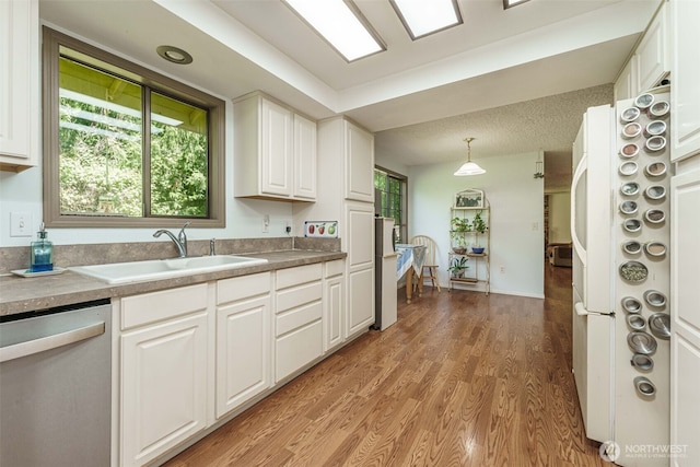 29139 NE Hammond Ct, Battle Ground, WA 98604 - kitchen featuring dishwasher, a sink, white cabinetry, and light wood-style flooring