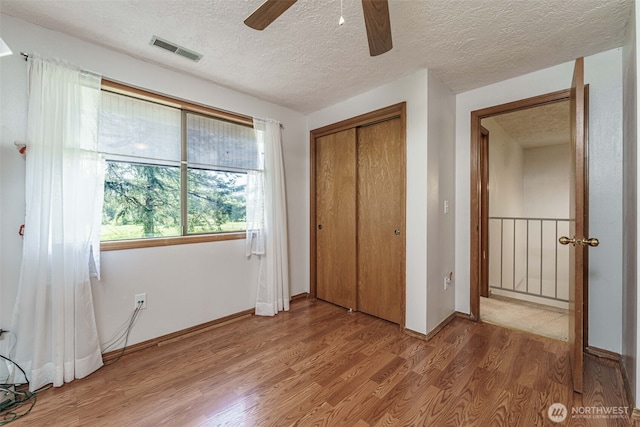 29139 NE Hammond Ct, Battle Ground, WA 98604 - unfurnished bedroom featuring light wood-type flooring, a textured ceiling, a closet, ceiling fan, and baseboards