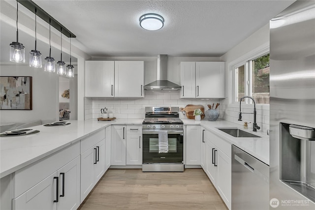 10209 65th Ave S, Seattle, WA 98178 - kitchen featuring wall chimney range hood, appliances with stainless steel finishes, a sink, white cabinets, and a textured ceiling