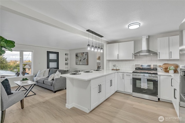 10209 65th Ave S, Seattle, WA 98178 - kitchen featuring stainless steel gas range, wall chimney range hood, light wood-style floors, a peninsula, and light countertops