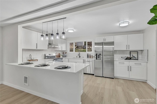 10209 65th Ave S, Seattle, WA 98178 - kitchen featuring stainless steel appliances, light wood-style floors, decorative backsplash, light countertops, and white cabinets