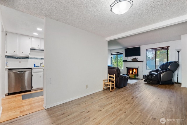 1801 Evergreen Park Ct SW Unit 8, Olympia, WA 98502 - living area with light wood-type flooring, a textured ceiling, recessed lighting, a warm lit fireplace, and baseboards