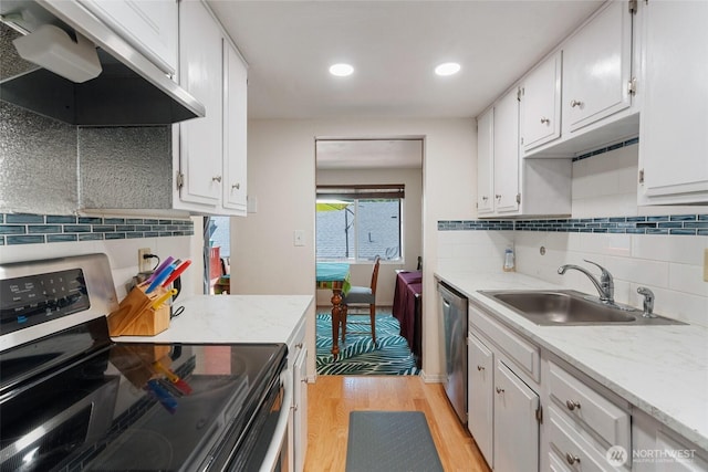 1801 Evergreen Park Ct SW Unit 8, Olympia, WA 98502 - kitchen with stainless steel appliances, wall chimney range hood, a sink, light wood-type flooring, and white cabinetry