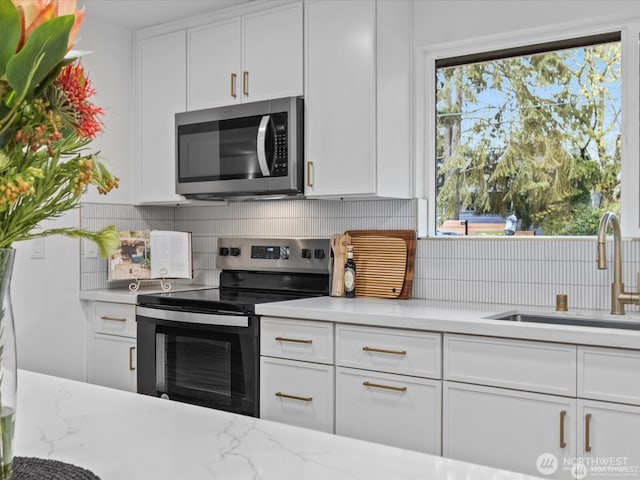 8421 240th St SW, Edmonds, WA 98020 - kitchen with stainless steel appliances, a sink, white cabinetry, backsplash, and light stone countertops