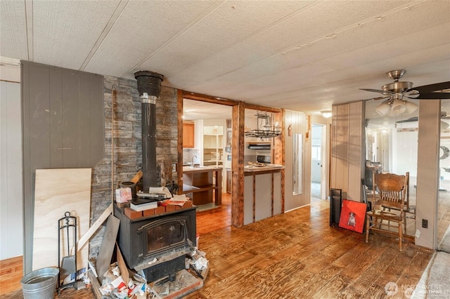 7503 189th Street Ct E Unit 12, Puyallup, WA 98375 - living room with a wood stove, wood finished floors, wooden walls, and a ceiling fan
