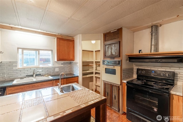 7503 189th Street Ct E Unit 12, Puyallup, WA 98375 - kitchen with black electric range, oven, brown cabinetry, and tasteful backsplash