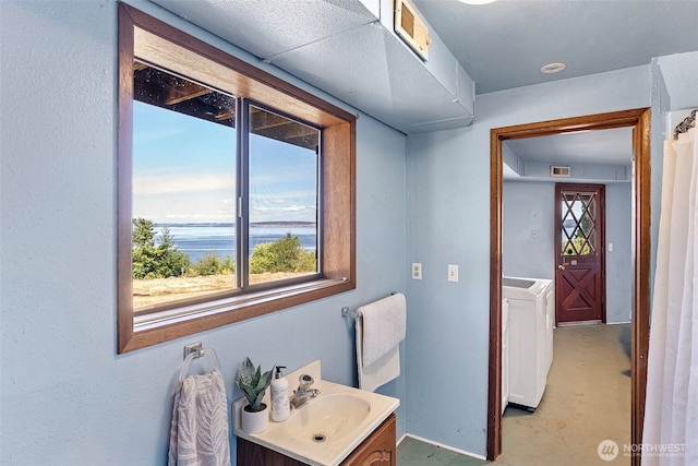 10601 87th Ct, Anderson Island, WA 98303 - bathroom featuring vanity, a water view, concrete floors, and washer / dryer