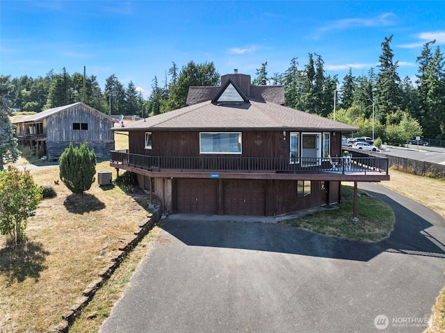 10601 87th Ct, Anderson Island, WA 98303 - view of front facade with asphalt driveway, a chimney, a shingled roof, an attached garage, and a wooden deck