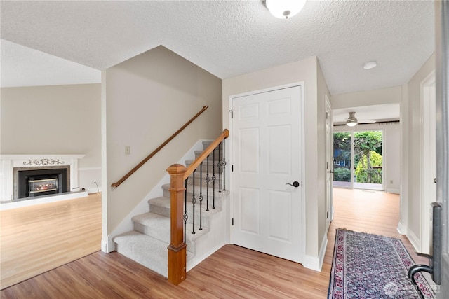 33205 32nd Pl SW, Federal Way, WA 98023 - foyer with light wood-type flooring, a glass covered fireplace, stairs, baseboards, and a textured ceiling