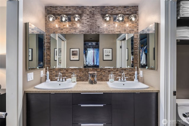 7008 155th Pl NE, Redmond, WA 98052 - bathroom featuring double vanity, a walk in closet, and tasteful backsplash