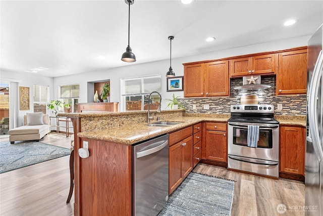 7328 Seashell Way, Blaine, WA 98230 - kitchen featuring stainless steel appliances, a sink, light wood-type flooring, a peninsula, and brown cabinets