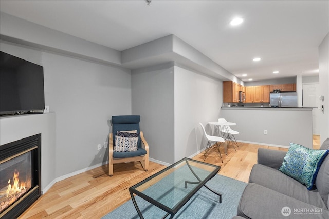 3318 30th Ave SW Unit B402, Seattle, WA 98126 - living area with light wood-style flooring, a glass covered fireplace, recessed lighting, and baseboards