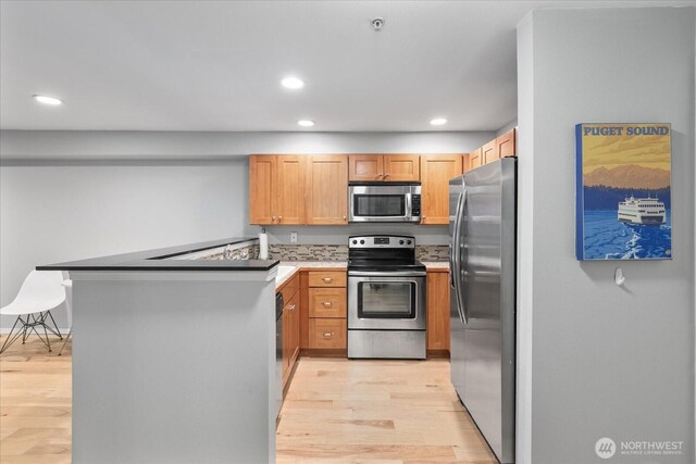 3318 30th Ave SW Unit B402, Seattle, WA 98126 - kitchen featuring appliances with stainless steel finishes, light wood-type flooring, a peninsula, recessed lighting, and light countertops