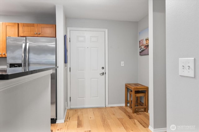 3318 30th Ave SW Unit B402, Seattle, WA 98126 - kitchen featuring light wood-style flooring, dark countertops, baseboards, and stainless steel fridge
