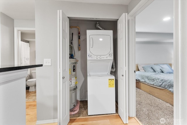 3318 30th Ave SW Unit B402, Seattle, WA 98126 - laundry area featuring stacked washing machine and dryer, light wood-style floors, and secured water heater