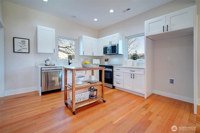 306 3rd St, Sultan, WA 98294 - kitchen featuring stainless steel appliances, white cabinets, light countertops, recessed lighting, and baseboards