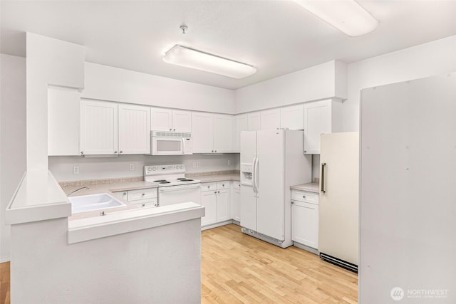 15026 40th Ave W Unit 13-104, Lynnwood, WA 98087 - kitchen featuring white appliances, light wood-type flooring, a peninsula, light countertops, and white cabinets