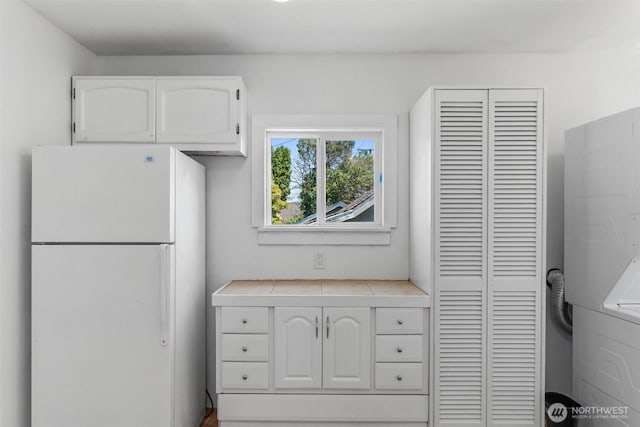 212 N Michigan St, Aberdeen, WA 98520 - kitchen with freestanding refrigerator, white cabinetry, tile countertops, and washer / dryer