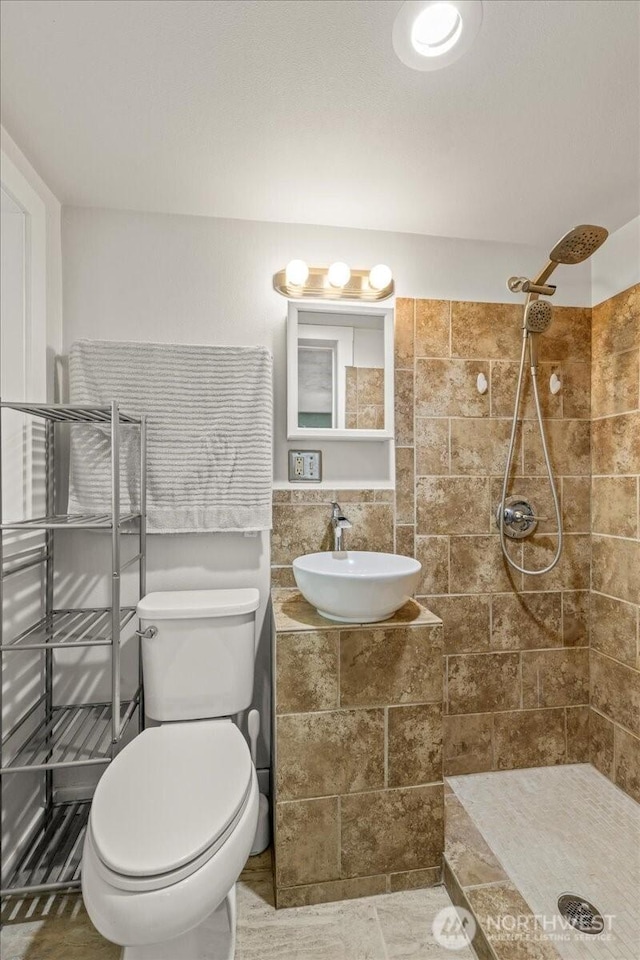 1412 Mcmillan Ave, Sumner, WA 98390 - bathroom featuring a sink, a tile shower, toilet, and tile walls