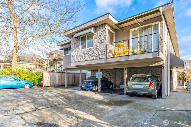 4456 Whitman Ave N, Seattle, WA 98103 - view of property with stone siding, covered parking, a balcony, and stucco siding