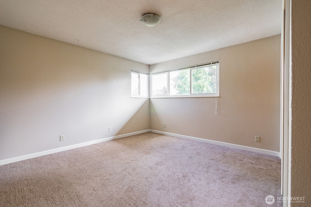 4456 Whitman Ave N, Seattle, WA 98103 - spare room with carpet flooring, a textured ceiling, and baseboards