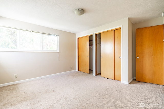 4456 Whitman Ave N, Seattle, WA 98103 - unfurnished bedroom with two closets, carpet floors, baseboards, and a textured ceiling