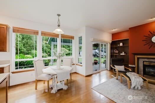 1155 Woods Rd SE, Port Orchard, WA 98366 - dining room with healthy amount of natural light, a glass covered fireplace, and light wood-style floors