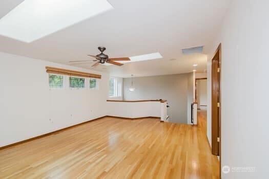 1155 Woods Rd SE, Port Orchard, WA 98366 - empty room with light wood-style floors, a ceiling fan, and a skylight