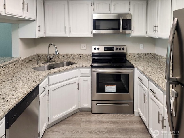 2611 NE 4th St Unit 234, Renton, WA 98056 - kitchen with appliances with stainless steel finishes, a sink, light wood-style floors, white cabinets, and light stone countertops