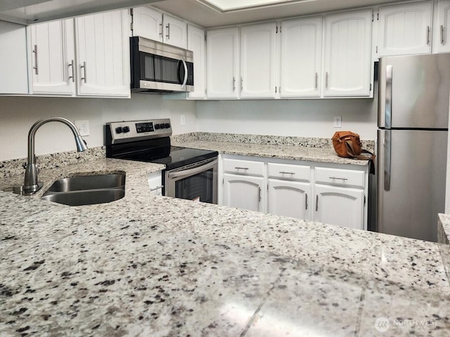 2611 NE 4th St Unit 234, Renton, WA 98056 - kitchen with stainless steel appliances, a sink, white cabinetry, and light stone countertops