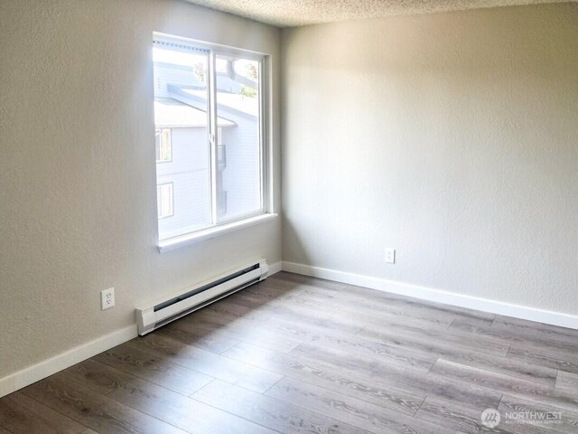 2611 NE 4th St Unit 234, Renton, WA 98056 - spare room with a baseboard radiator, plenty of natural light, wood finished floors, baseboards, and a textured ceiling