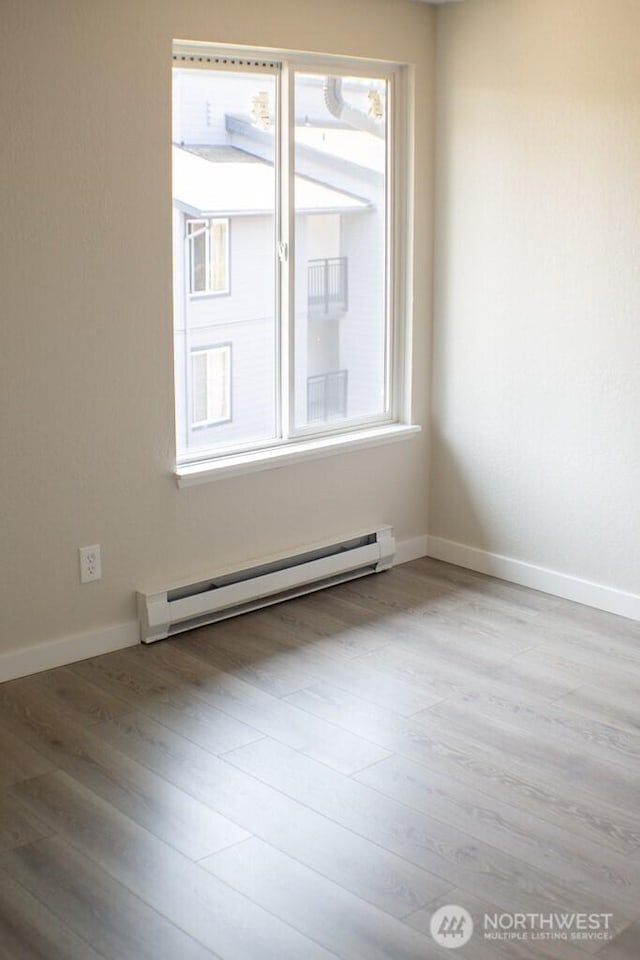2611 NE 4th St Unit 234, Renton, WA 98056 - empty room featuring a baseboard radiator, wood finished floors, and baseboards