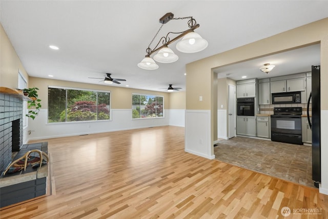 104 Hawthorn Ln, Shelton, WA 98584 - unfurnished living room featuring a ceiling fan, a fireplace, a wainscoted wall, light wood-type flooring, and recessed lighting