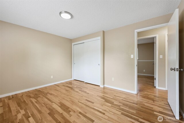 104 Hawthorn Ln, Shelton, WA 98584 - unfurnished bedroom featuring light wood-style flooring, a textured ceiling, baseboards, and a closet