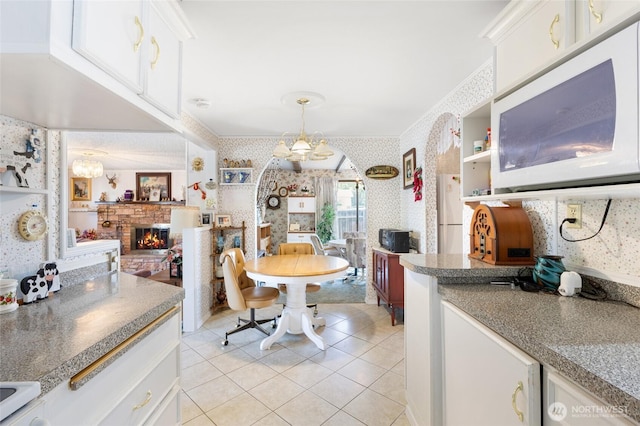 515 N Clark Rd, Moses Lake, WA 98837 - dining space featuring wallpapered walls, light tile patterned flooring, a chandelier, a glass covered fireplace, and ornamental molding