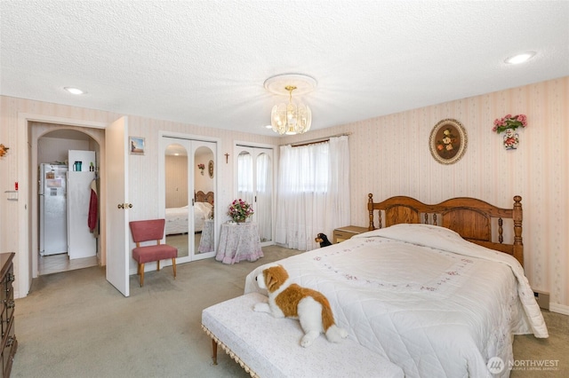 515 N Clark Rd, Moses Lake, WA 98837 - bedroom with light colored carpet, wallpapered walls, a chandelier, multiple closets, and a textured ceiling