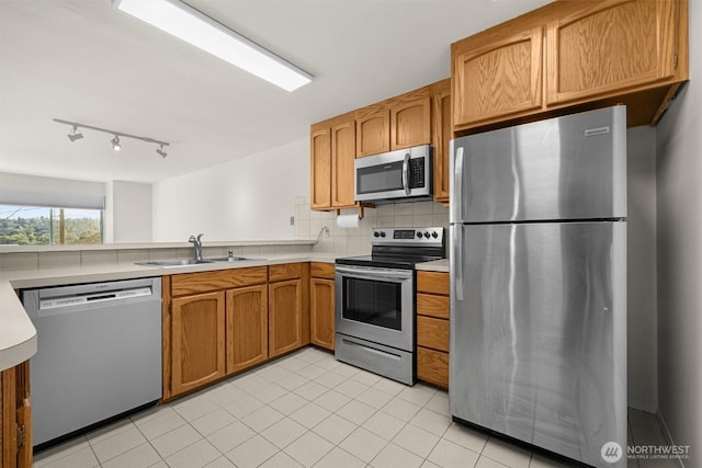 1964 26th Ave W Unit 102, Seattle, WA 98199 - kitchen featuring stainless steel appliances, a sink, decorative backsplash, light countertops, and light tile patterned floors
